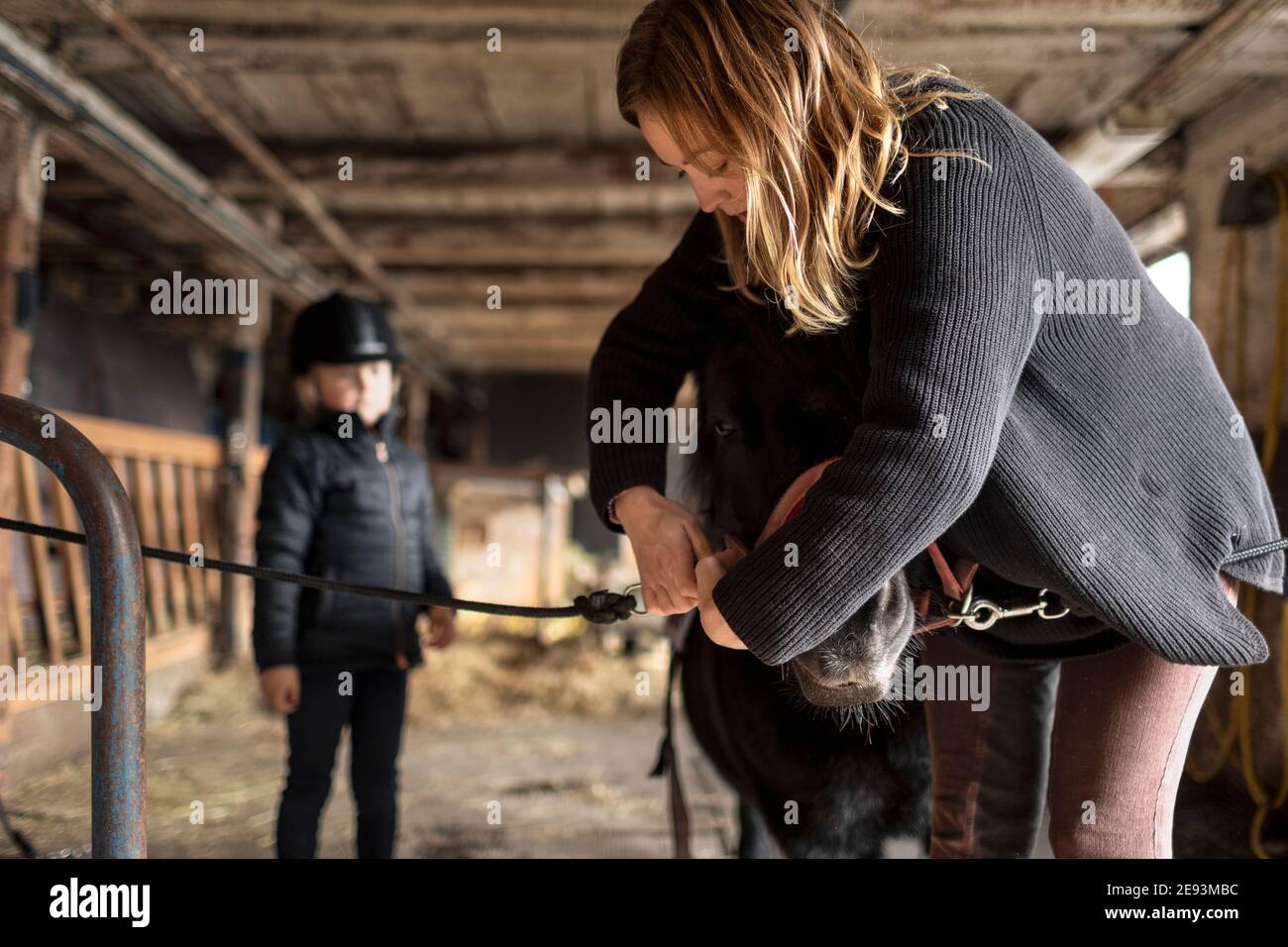 Mère avec fille préparant le poney pour le tour Banque D'Images
