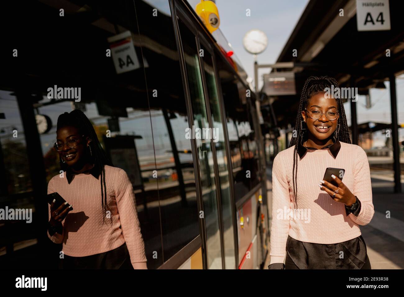 Jeune femme utilisant un téléphone cellulaire à la gare routière Banque D'Images