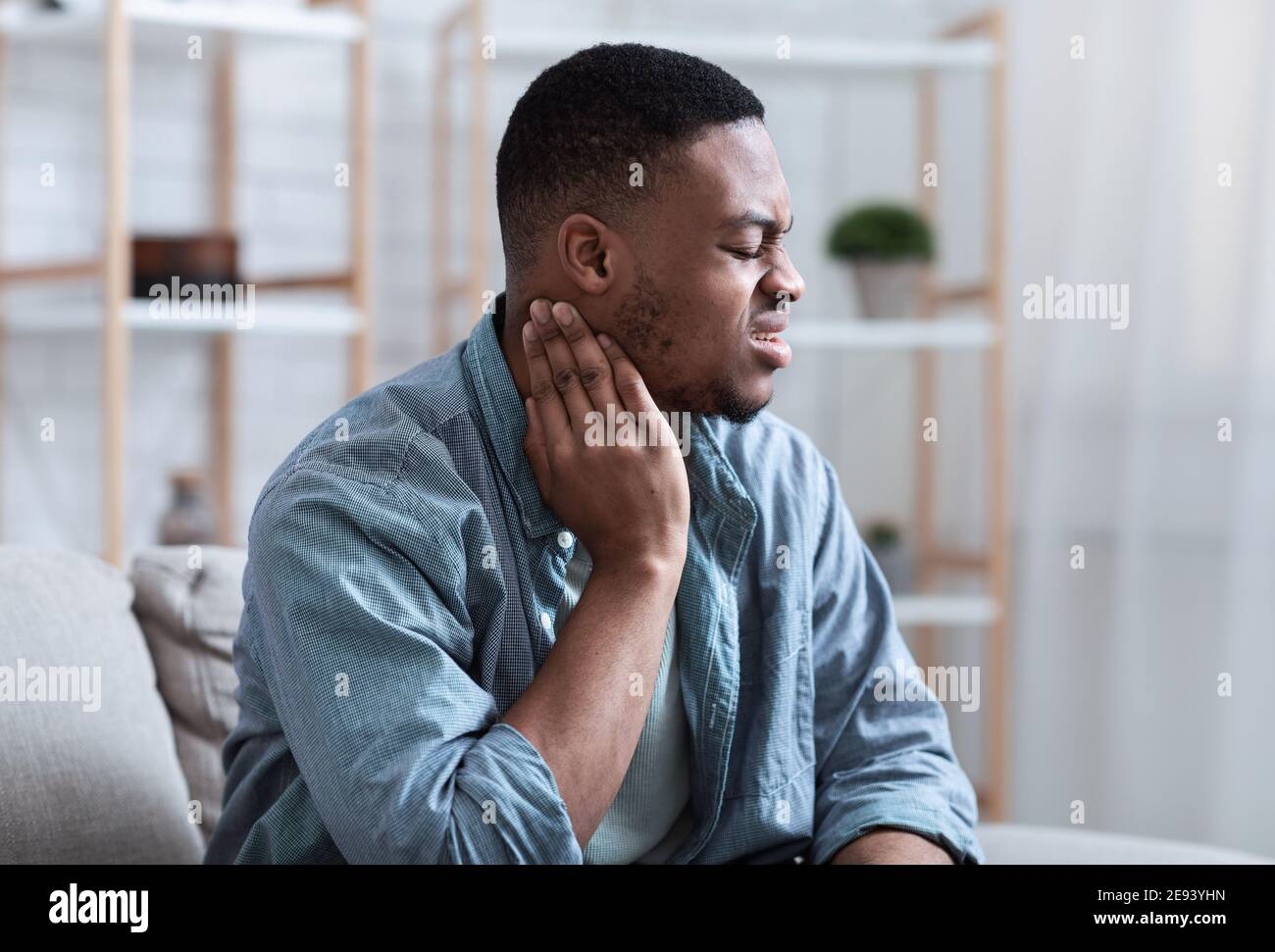 African Guy massing cou souffrant de douleur à la maison Banque D'Images