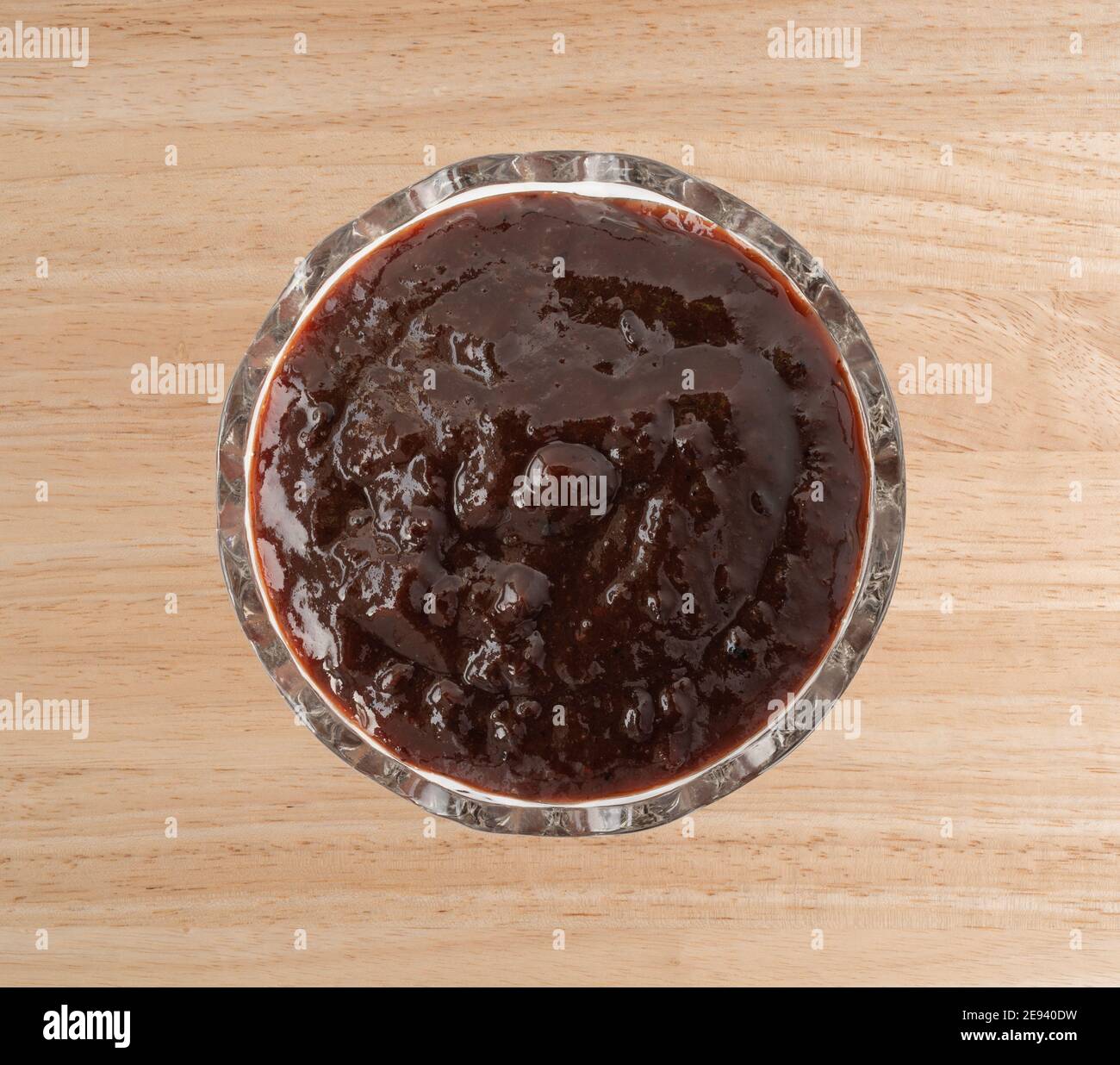 Vue de dessus d'un bol en verre rempli de beurre de prune sur un plan d'examen en bois. Banque D'Images