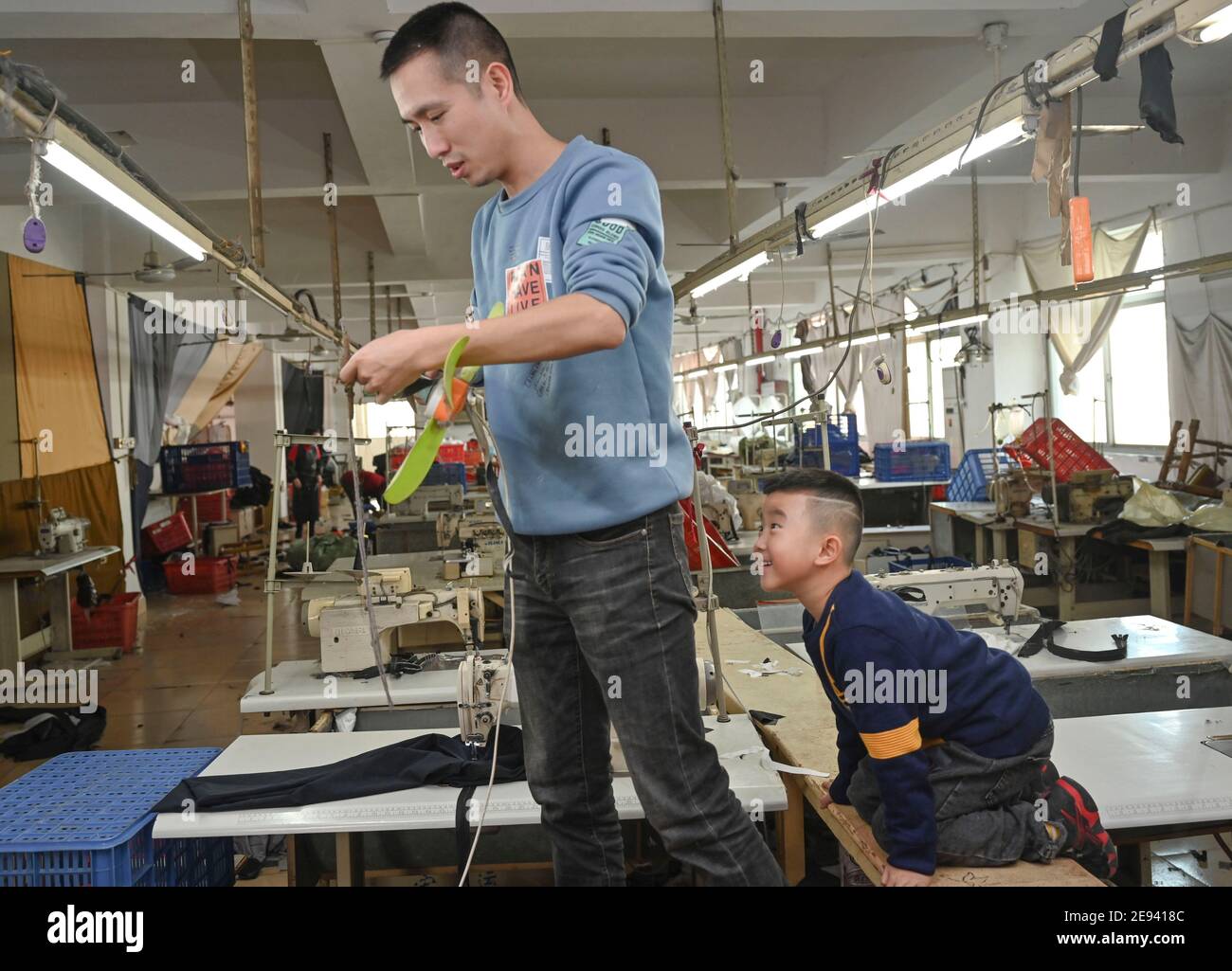 (210202) -- FUZHOU, 2 février 2021 (Xinhua) -- Congcong interagit avec son père Huang Hailong dans une usine de vêtements à Shishi, dans la province de Fujian, dans le sud-est de la Chine, le 26 janvier 2021. Suite à la résurgence sporadique des cas de COVID-19, de nombreux endroits en Chine ont encouragé les résidents et les travailleurs migrants à rester mis en place pour célébrer le Festival du printemps, pour réduire le flux de personnel et freiner la propagation du coronavirus pendant la période des fêtes. Huang Hailong, un travailleur migrant de Shishi, a déclaré que ce serait sa première fois au cours des dernières années de passer les vacances à Shishi au lieu de sa ville natale dans le Cit Banque D'Images