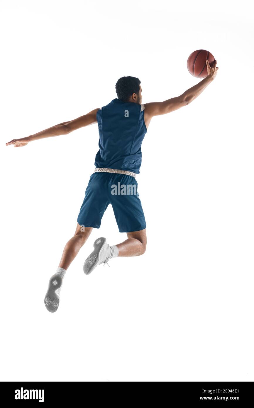Vol élevé. Jeune joueur de basket-ball arabe musclé en action, le mouvement isolé sur fond blanc. Concept de sport, de mouvement, d'énergie et de mode de vie dynamique et sain. Formation, pratique. Banque D'Images