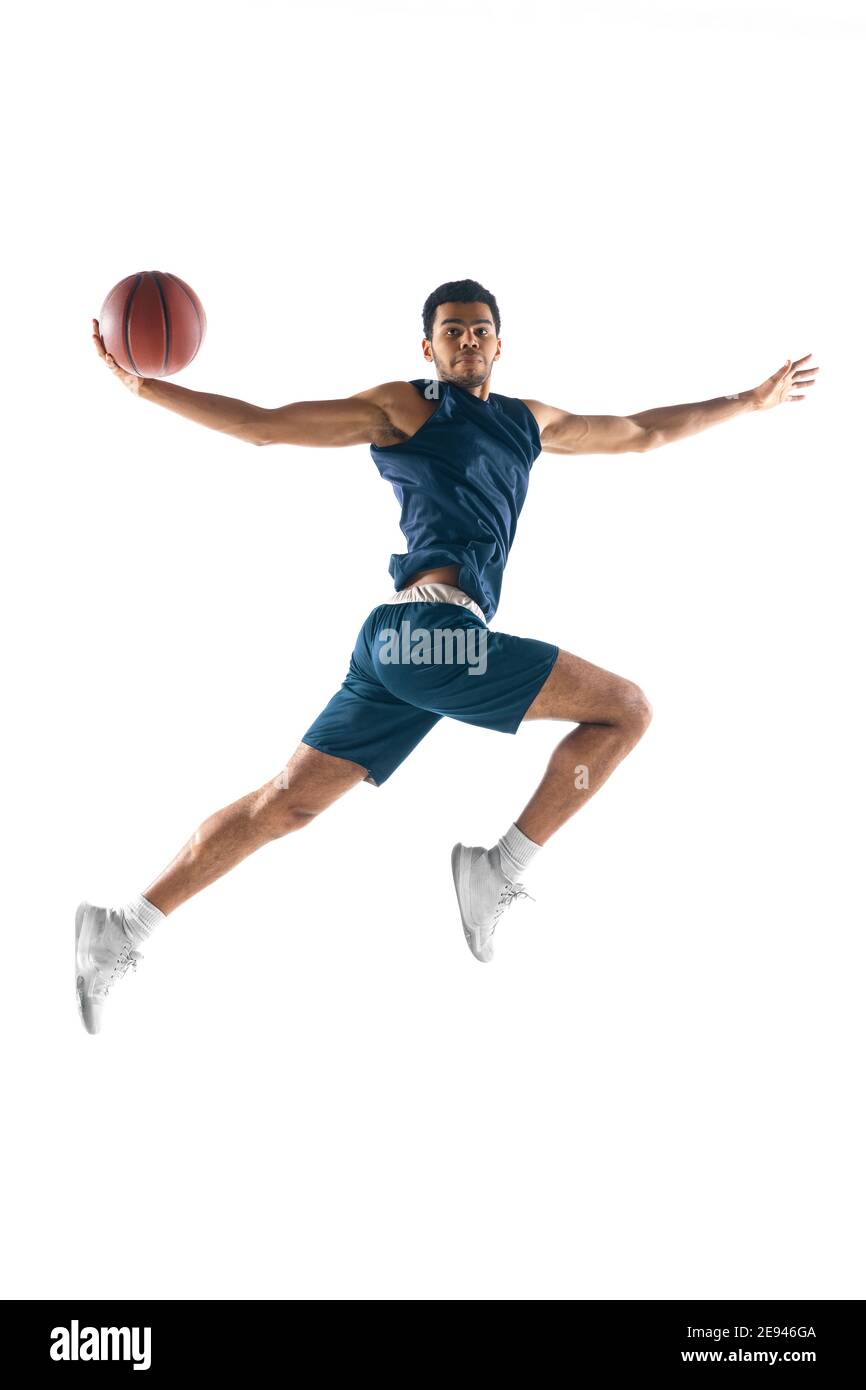 Vol élevé. Jeune joueur de basket-ball arabe musclé en action, le mouvement isolé sur fond blanc. Concept de sport, de mouvement, d'énergie et de mode de vie dynamique et sain. Formation, pratique. Banque D'Images