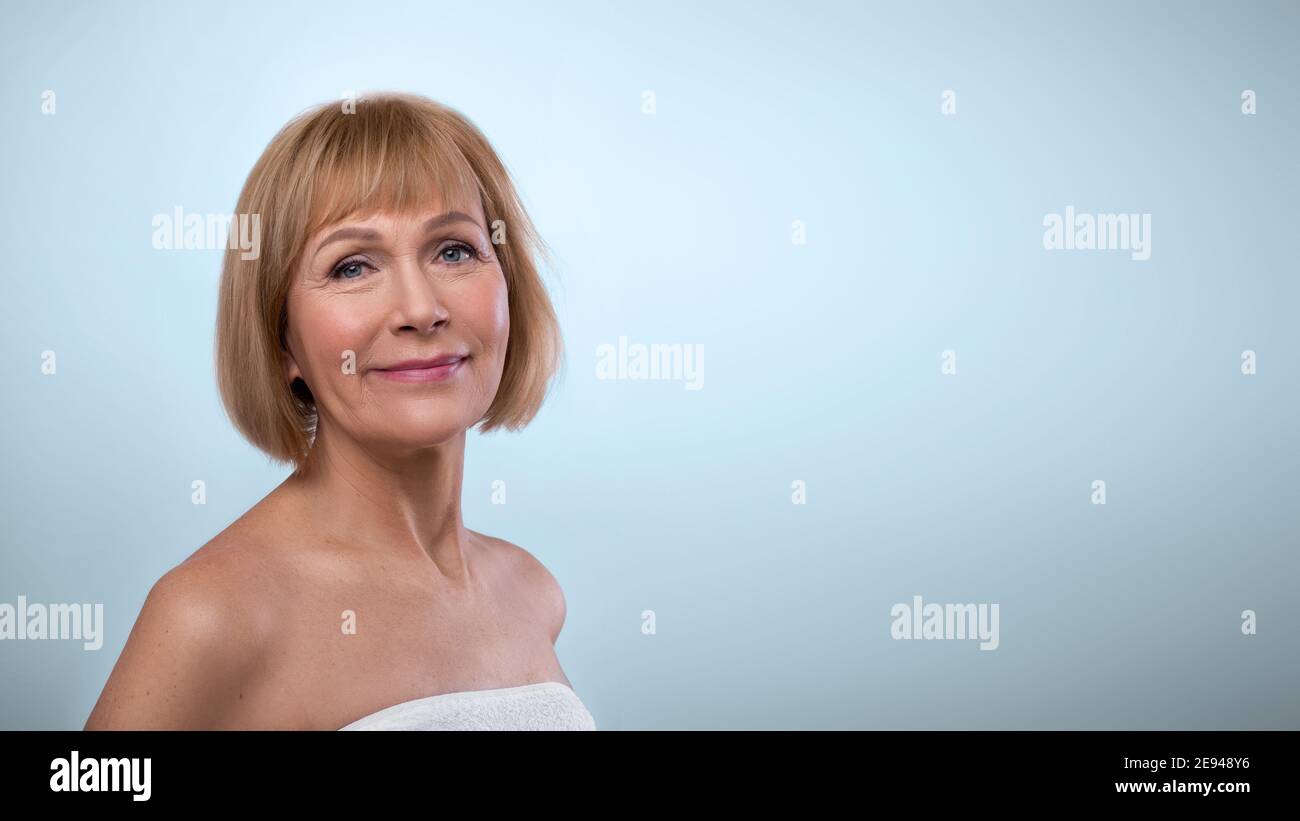 Beauté naturelle. Portrait d'une femme âgée féminine dans une serviette à la peau soyeuse et douce, posé sur un fond bleu clair Banque D'Images