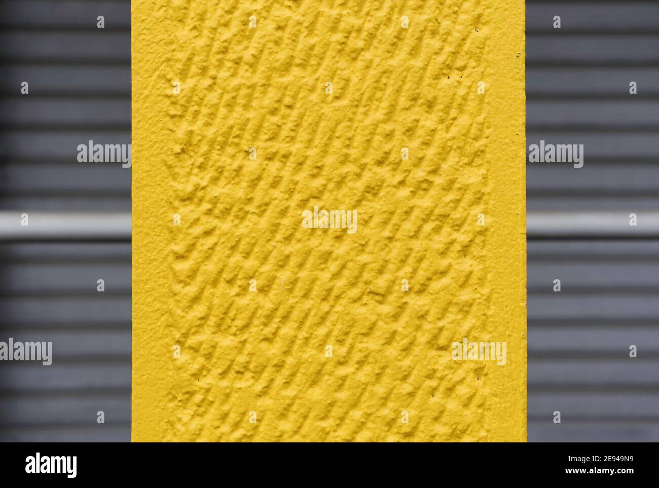 Fond en béton agréable ton jaune sur les volets gris fermés - Texture de la surface du mur - Grunge fond de couleur lumineuse dans gris urbain Banque D'Images