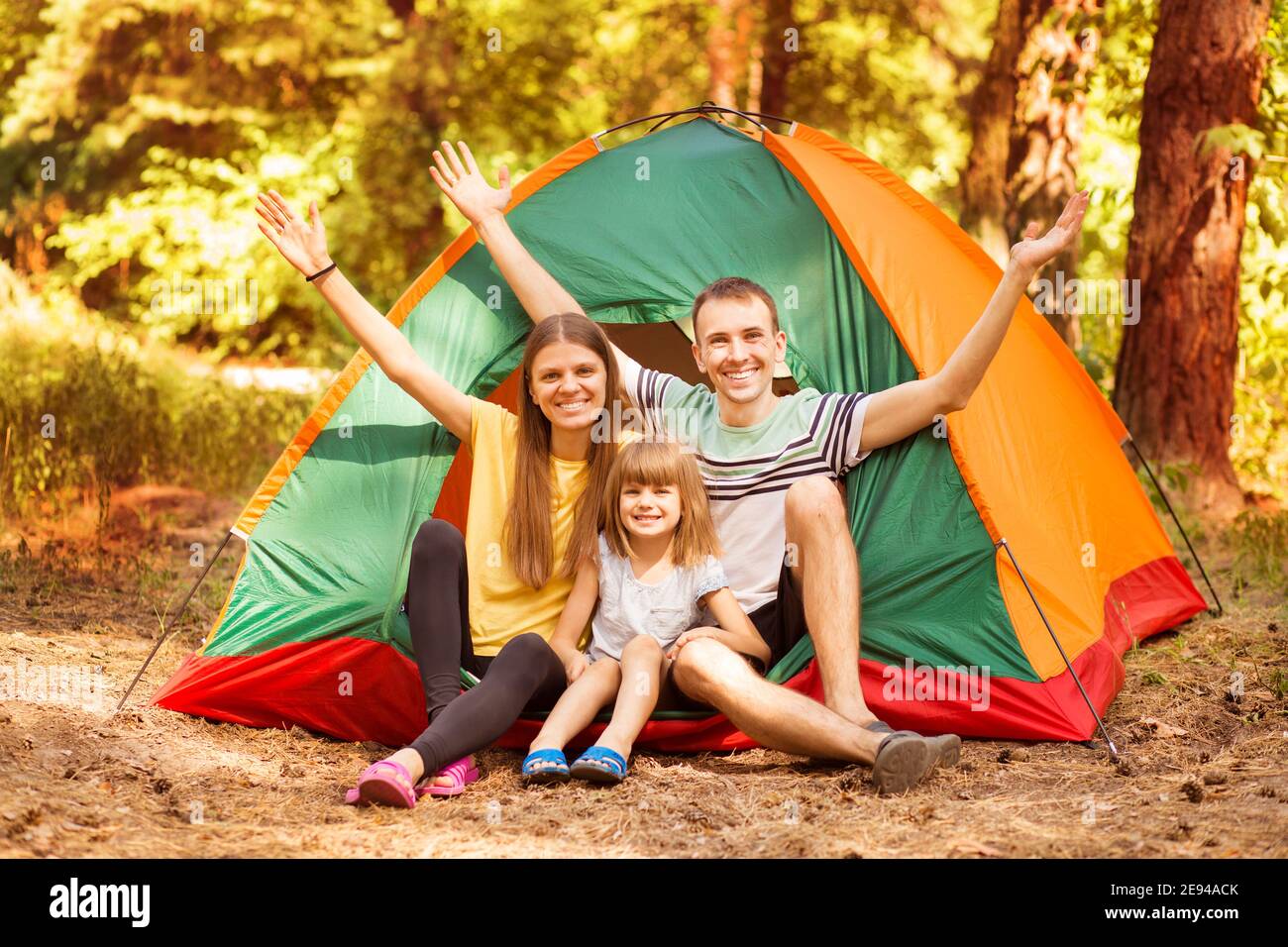 Famille de trois personnes campant et ayant du plaisir ensemble dans la forêt d'été. Camping vacances. Banque D'Images