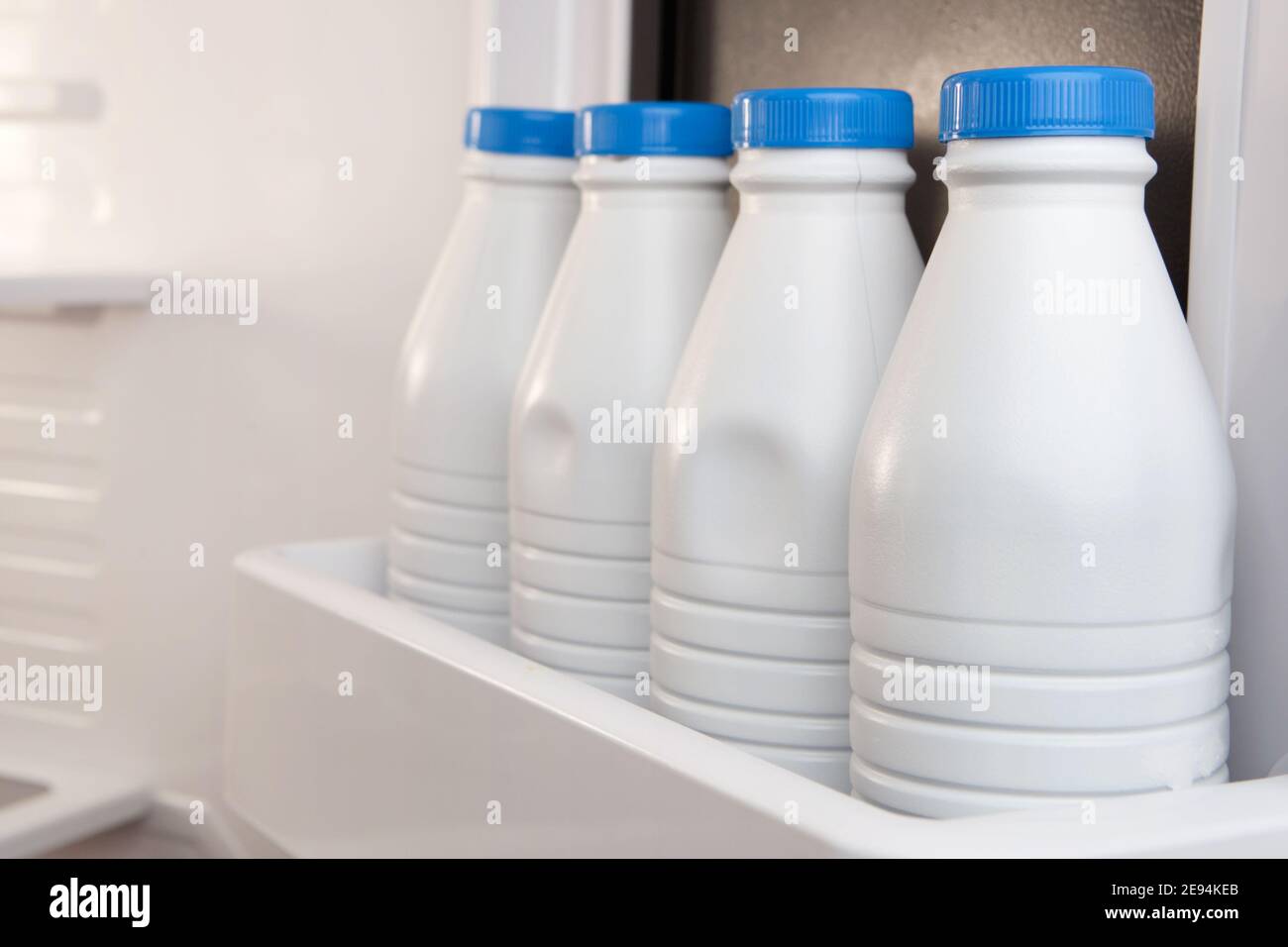 Groupe de bidons de lait en plastique stockés et alignés dans la porte du réfrigérateur. Le calcium est bon pour votre santé Banque D'Images