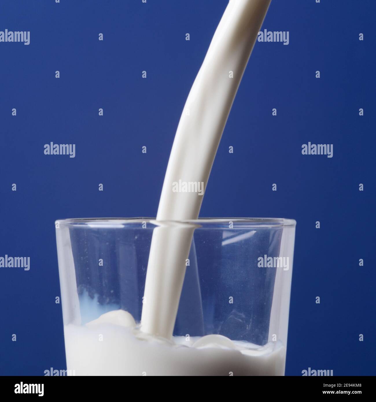 gros plan du lait versé dans un verre et isolé sur du bleu arrière-plan Banque D'Images