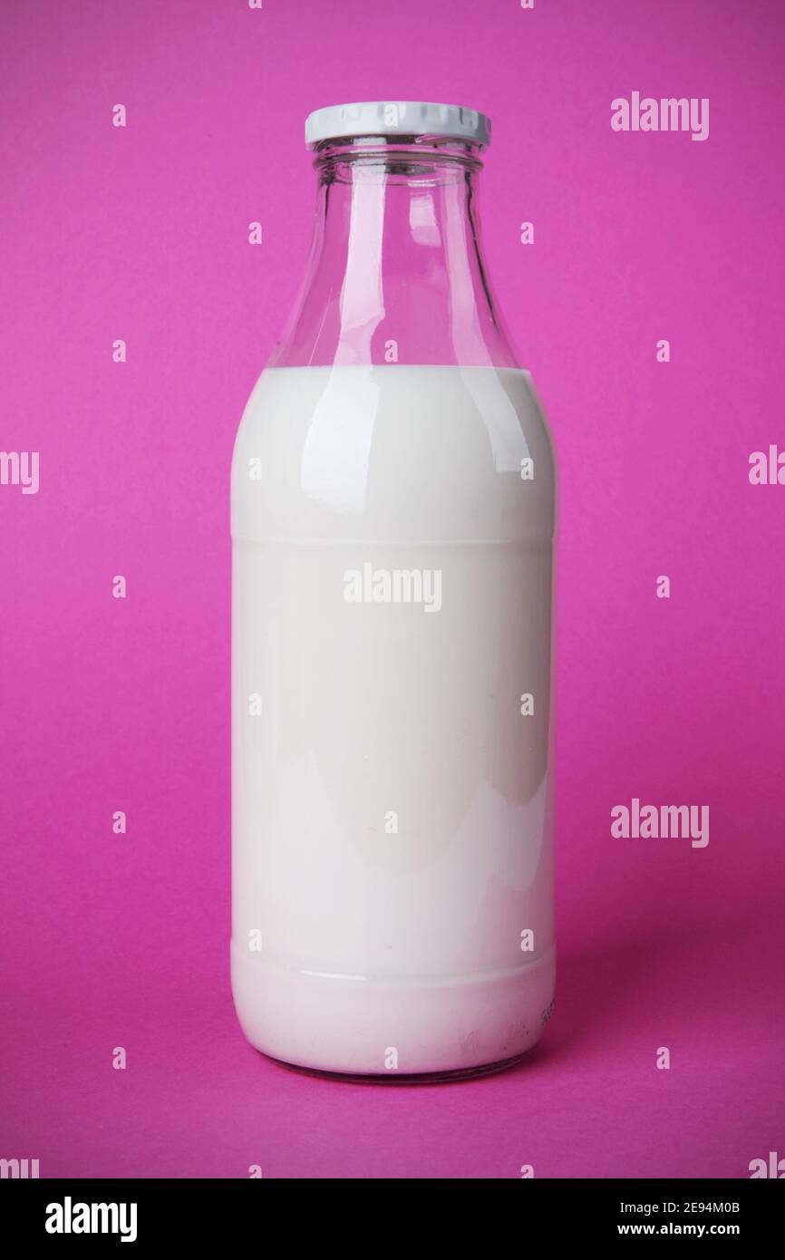 Bon petit déjeuner avec une bouteille en verre de lait frais. Le calcium est bon pour votre santé. Photo sur fond rose avec ombre Banque D'Images