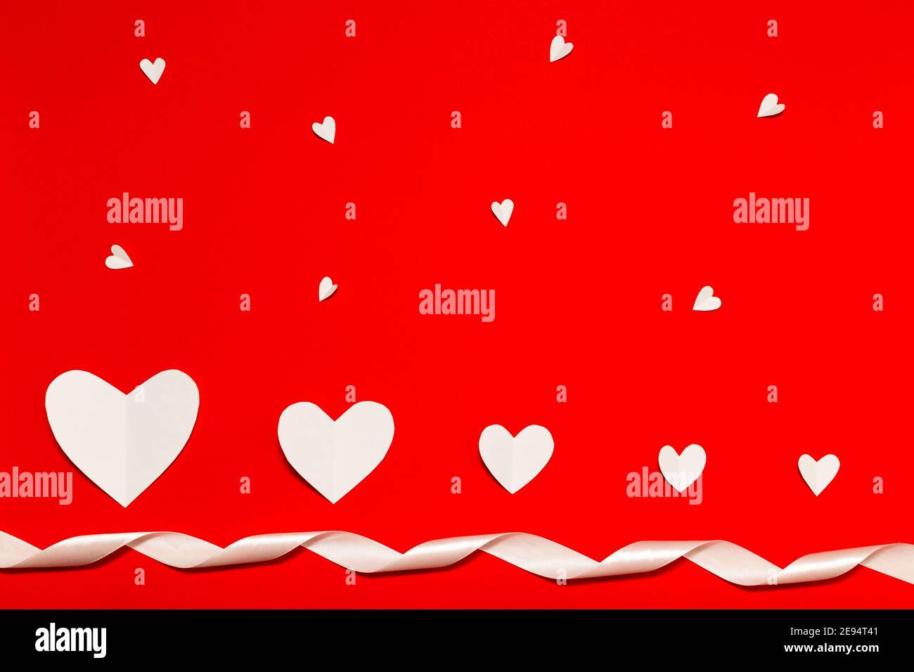 Coeurs en papier blanc avec ruban blanc sur fond rouge et pose à plat. Composition de la Saint-Valentin. Concept de vacances. Banque D'Images