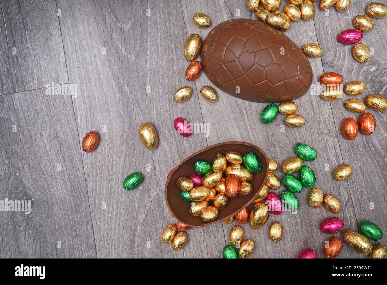 Pile ou groupe de plusieurs couleurs et différentes tailles d'oeufs de pâques au chocolat enveloppés de papier d'aluminium coloré dans le rose, le rouge, l'or et le vert. Grandes moitiés d'un bro Banque D'Images