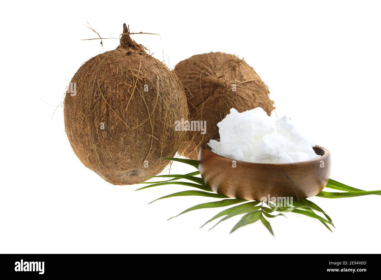 Huile de coco pure organique. Huile de noix de coco dans une tasse en bois et noix de coco fruits avec feuille de palmier verte isolée sur fond blanc Banque D'Images