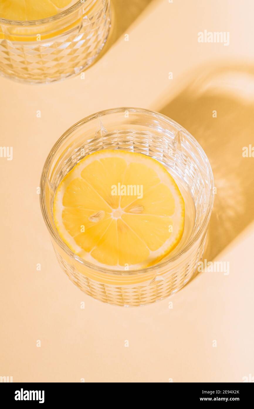 Verre d'eau avec citron sur fond pastel Banque D'Images