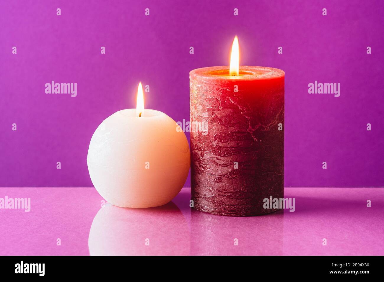 Bougies rouges et blanches avec une flamme sur fond violet Banque D'Images