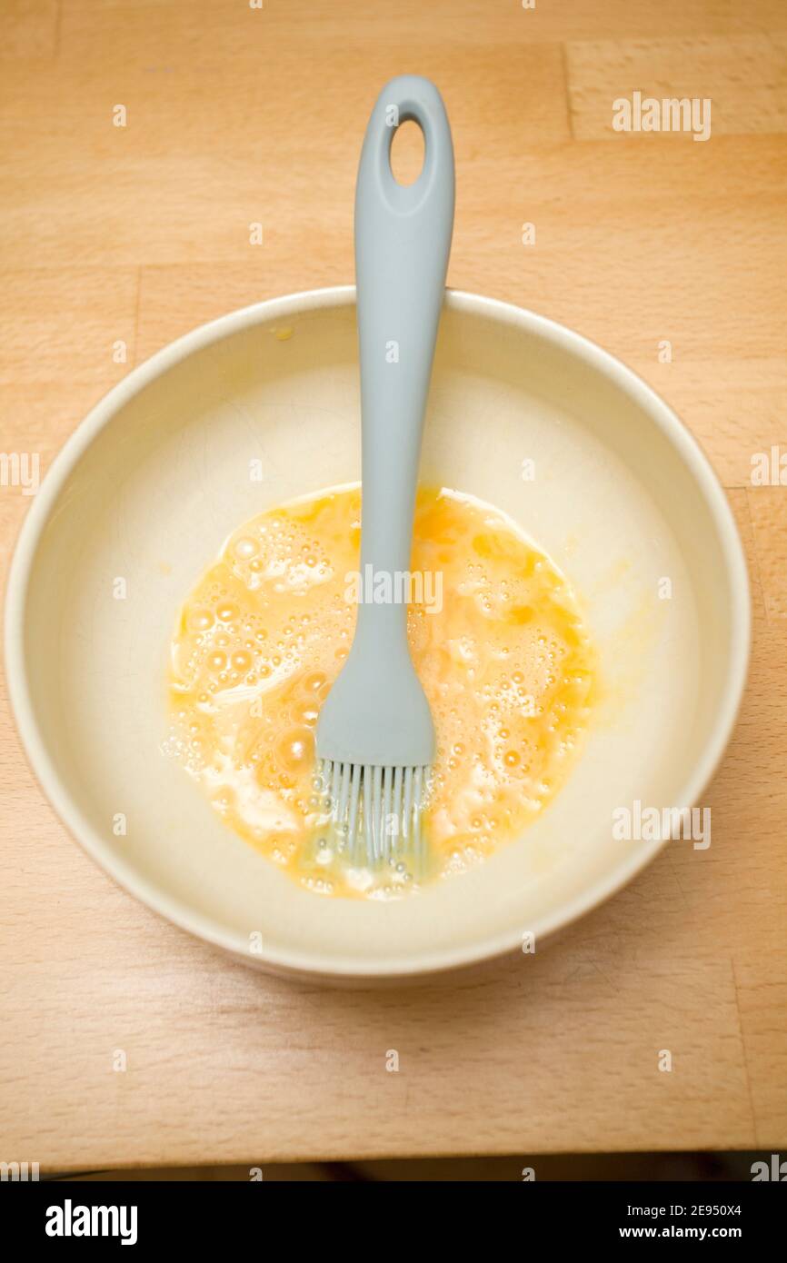 Pinceau à pâtisserie dans un bol de jaune d'œuf près de up.uk Banque D'Images