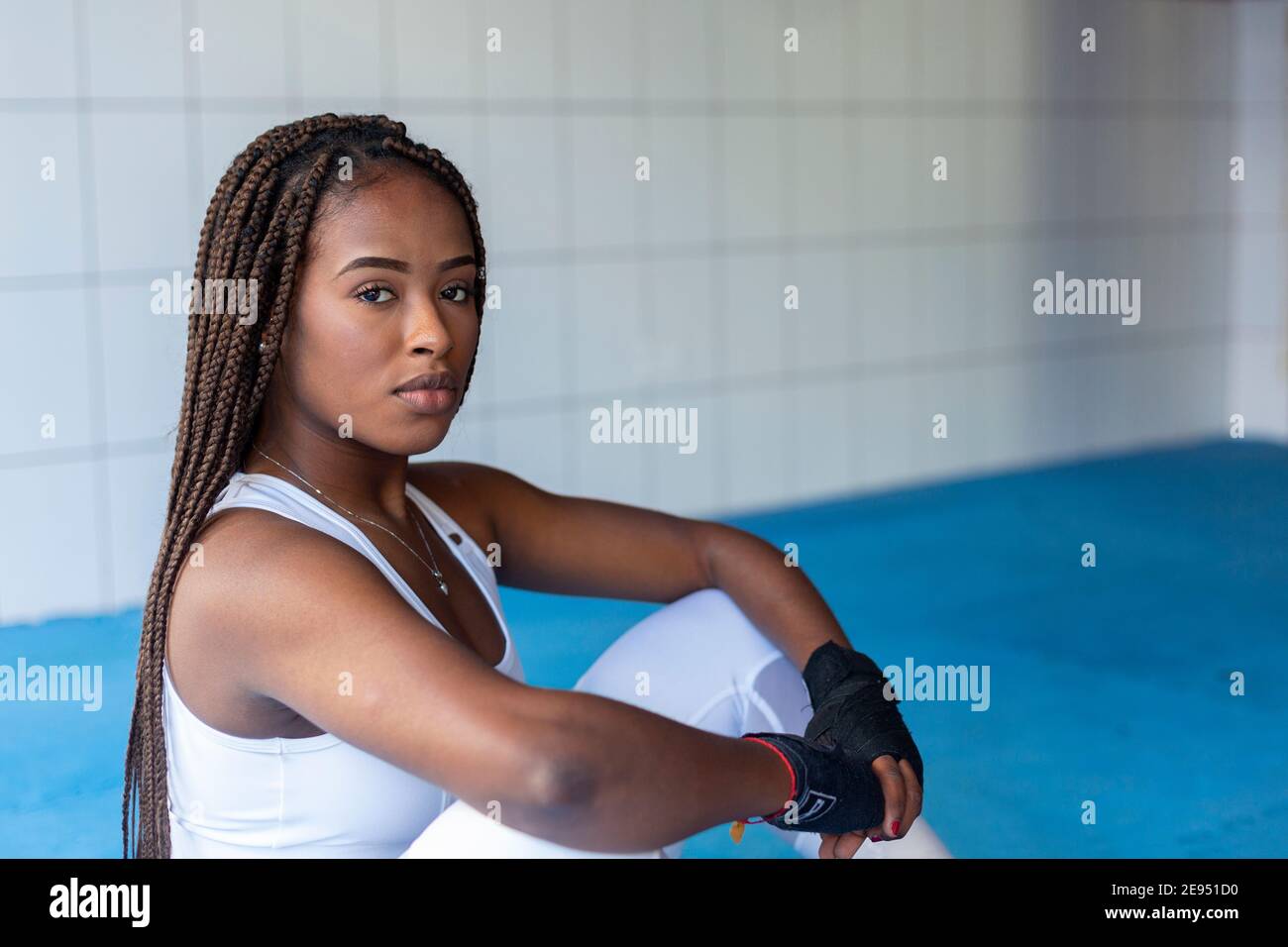 Portrait de la belle fille afro-américaine regardant l'appareil photo assis pour s'entraîner à l'intérieur d'une salle de gym. Banque D'Images