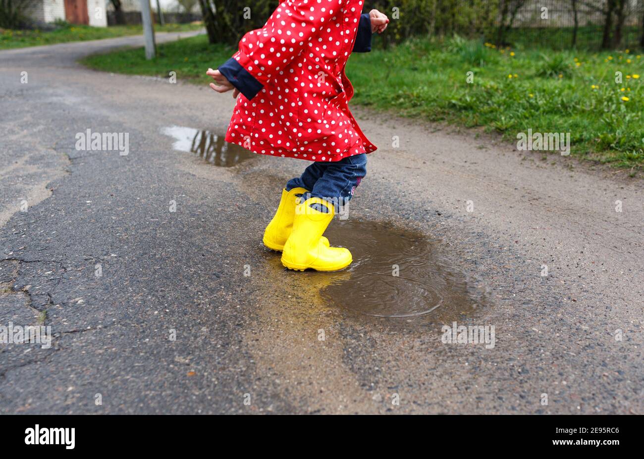 Une petite fille en bottes jaunes saute sur les flaques de printemps, gros  plan Photo Stock - Alamy