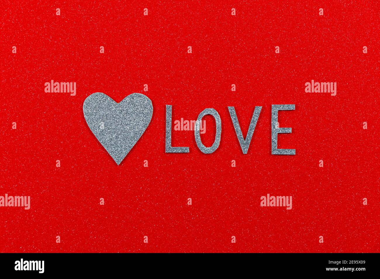 Texte « Love » et coeur argenté sur rouge texturé Banque D'Images
