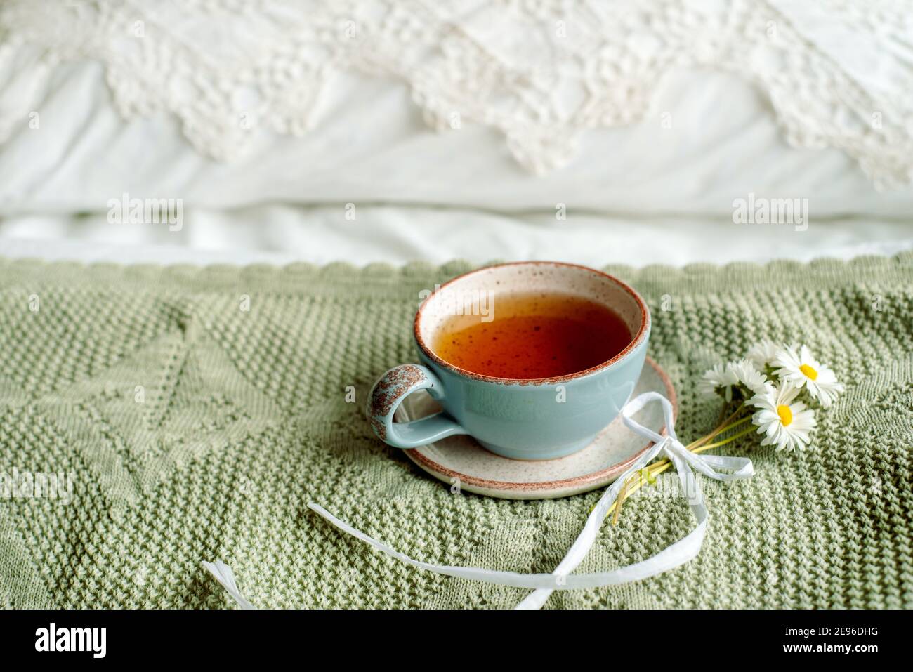 Une tasse de café et un livre ouvert sur un lit ouvert blanc. Petit-déjeuner le matin. Journée chaleureuse et lumineuse Banque D'Images