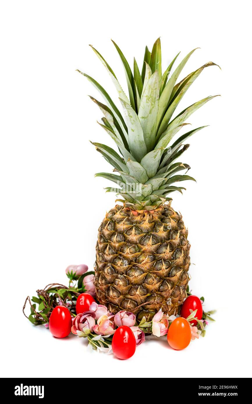 Composition de Pâques d'ananas, de couronne de fleurs et d'oeufs colorés isolés sur fond blanc Banque D'Images