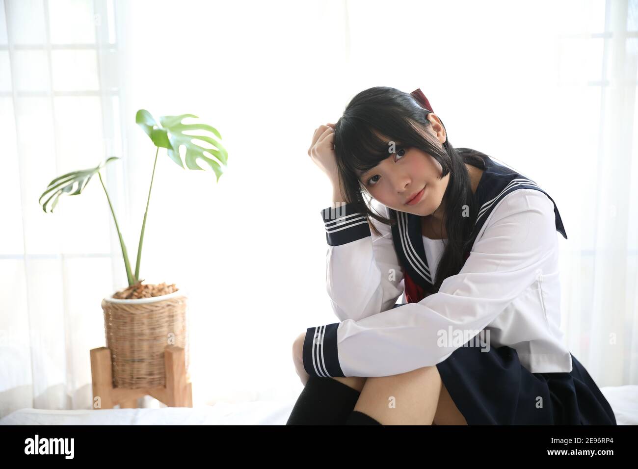 fille d'école japonaise assise sur la chambre dans un ton blanc Banque D'Images