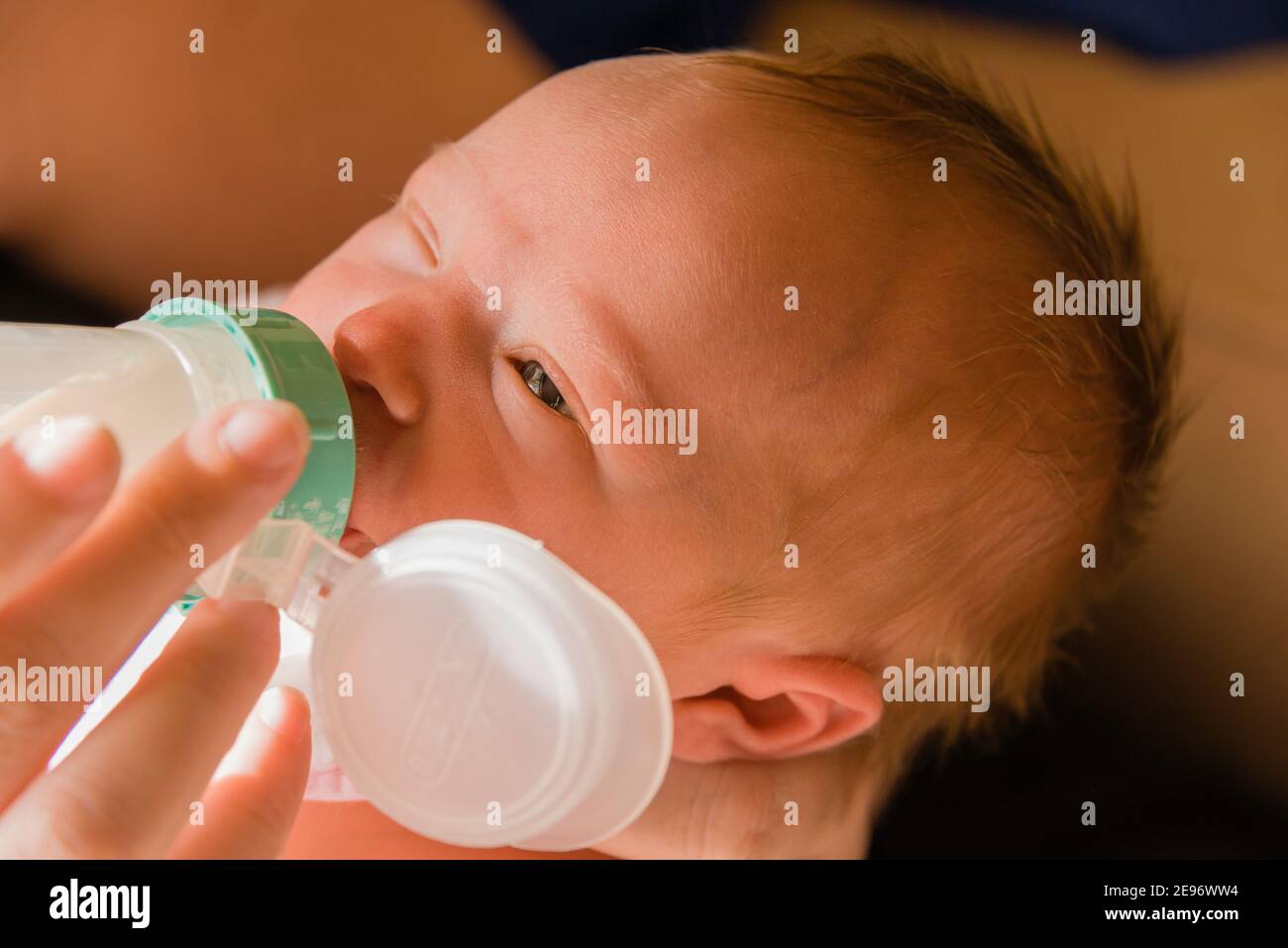 La Mere Allaite Le Biberon A Une Jeune Fille D Une Semaine Dans La Chambre De Bebe Eclairee Au Soleil Photo Stock Alamy