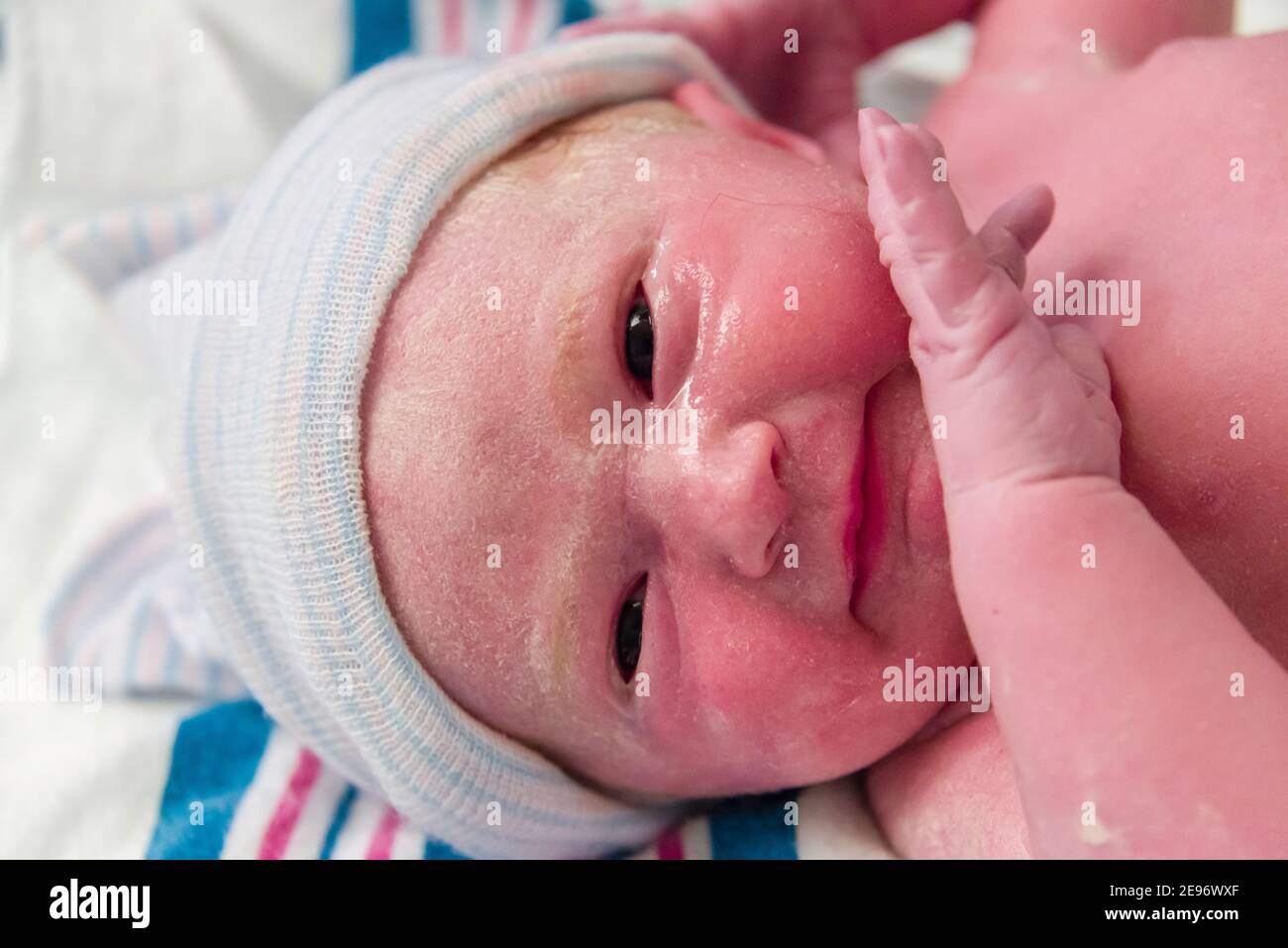 Visage avec les yeux ouverts de la jeune fille de nouveau-né dans une salle d'accouchement d'hôpital. Banque D'Images