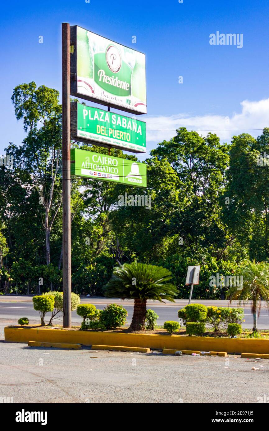 Un panneau de magasin de proximité se trouve le long de la route, au milieu des palmiers et des plantes tropicales de la République dominicaine. Banque D'Images