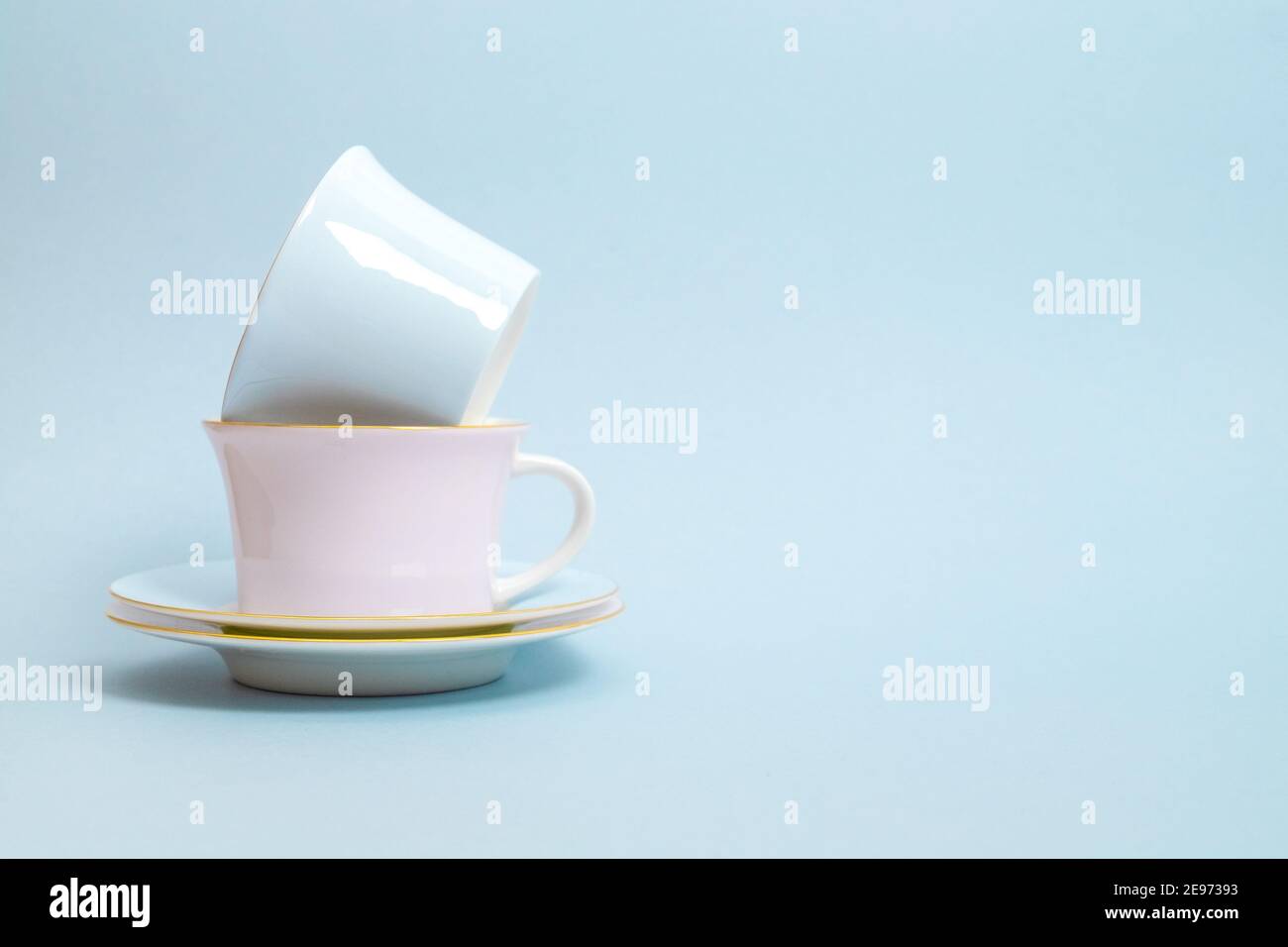 Deux tasses en porcelaine et soucoupes pour le thé ou le café aux couleurs bleu et rose sont posées sur un fond bleu. Couleurs pastel. Mise au point sélective. Copier l'espace. Banque D'Images