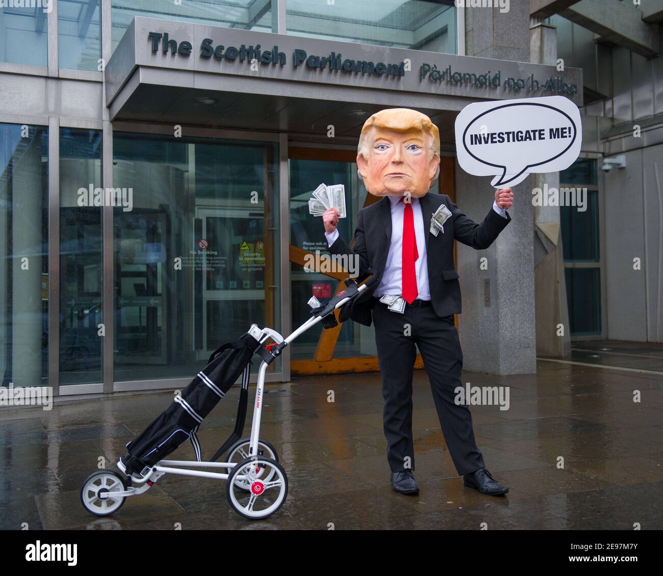 Édimbourg, Écosse, Royaume-Uni. 3 février 2021. Photo : avant un débat et un vote au Parlement écossais pour décider si le gouvernement écossais doit enquêter sur le financement par Donald Trump des terrains de golf écossais, les militants dépeigneront un faux Trump portant une tête géante, une cravate rouge et portant un panneau indiquant « Investigate Me! » En dehors du Parlement écossais. Il va également traîner son sac de golf débordant avec des billets de dollar. Crédit : Colin Fisher/Alay Live News Banque D'Images