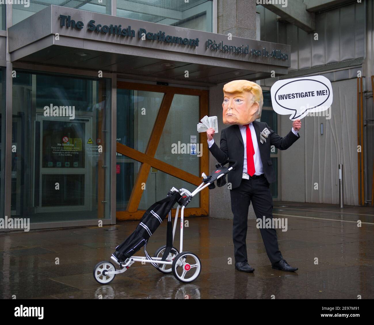 Édimbourg, Écosse, Royaume-Uni. 3 février 2021. Photo : avant un débat et un vote au Parlement écossais pour décider si le gouvernement écossais doit enquêter sur le financement par Donald Trump des terrains de golf écossais, les militants dépeigneront un faux Trump portant une tête géante, une cravate rouge et portant un panneau indiquant « Investigate Me! » En dehors du Parlement écossais. Il va également traîner son sac de golf débordant avec des billets de dollar. Crédit : Colin Fisher/Alay Live News Banque D'Images