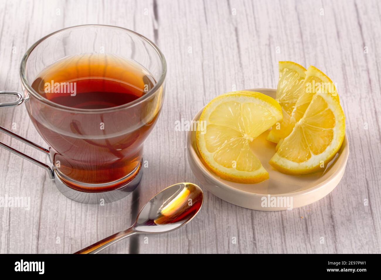 infusion dans le verre sur table en bois dans un fond clair et blanc, des tranches de citron et une cuillère à café. concept temps de thé Banque D'Images