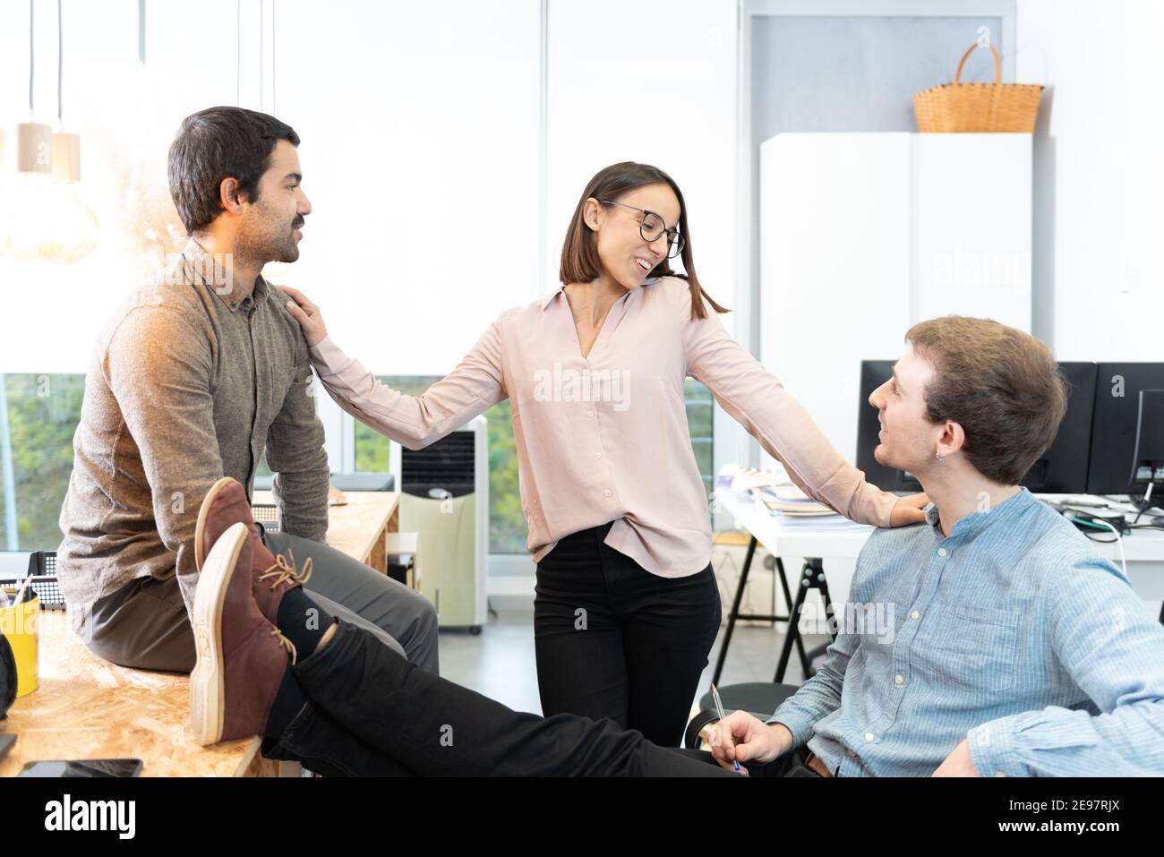 Trois jeunes collègues de travail différents discutent en toute sérénité au bureau. Banque D'Images