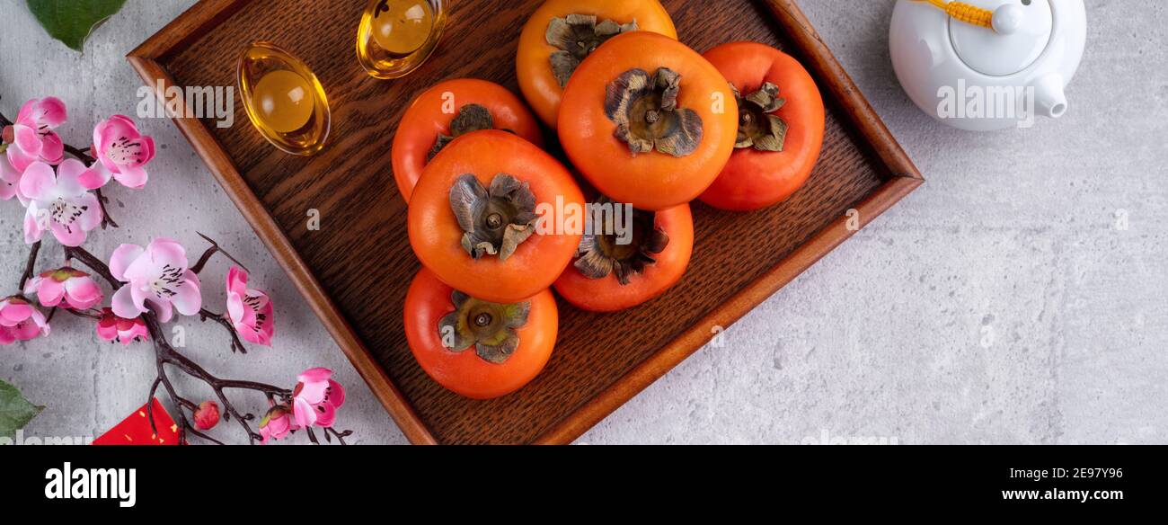 Persimmons frais sur fond de table gris pour la conception chinoise de fruits de la nouvelle année, les mots sur la pièce de monnaie d'or signifie le nom de la dynastie qu'il a fait. Banque D'Images