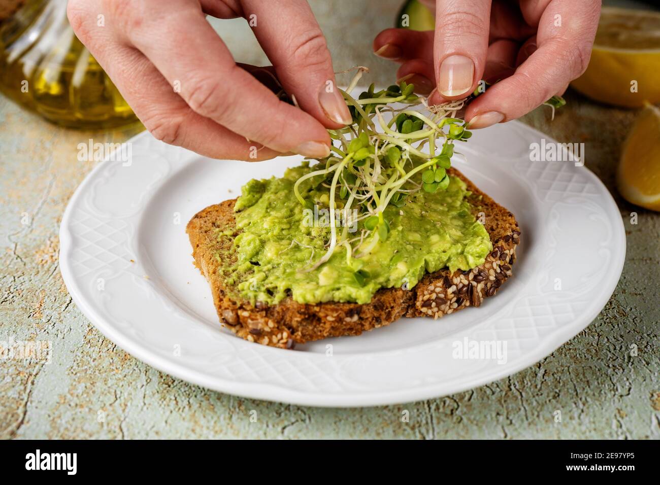 Des femmes mettent des micro-verts sur des toasts d'avocat Banque D'Images