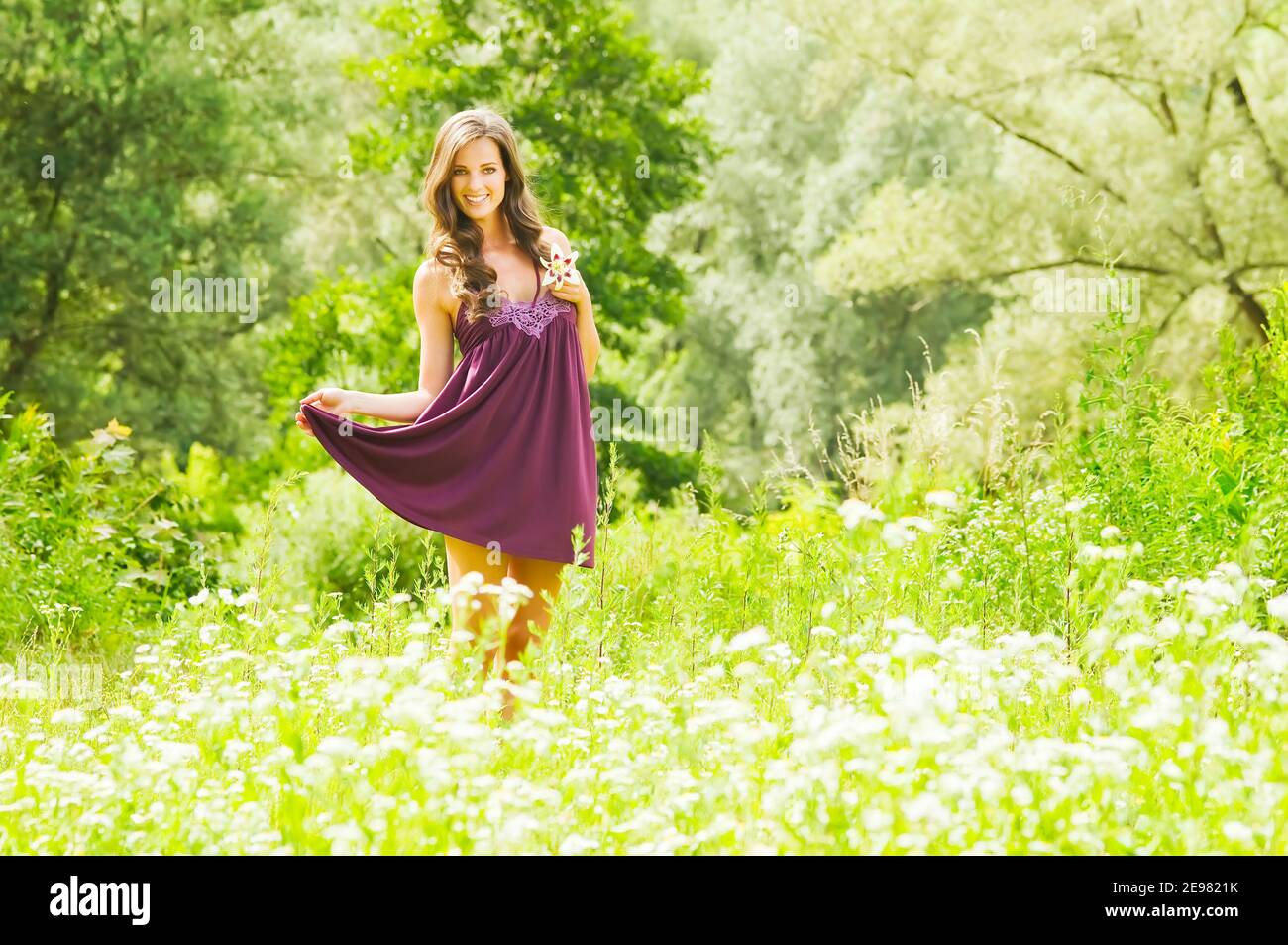 Jeune femme souriante en robe bordeaux avec fleur sur fond de parc vert  d'été. Belle fille heureuse en bonne santé appréciant la liberté dehors  dans na Photo Stock - Alamy