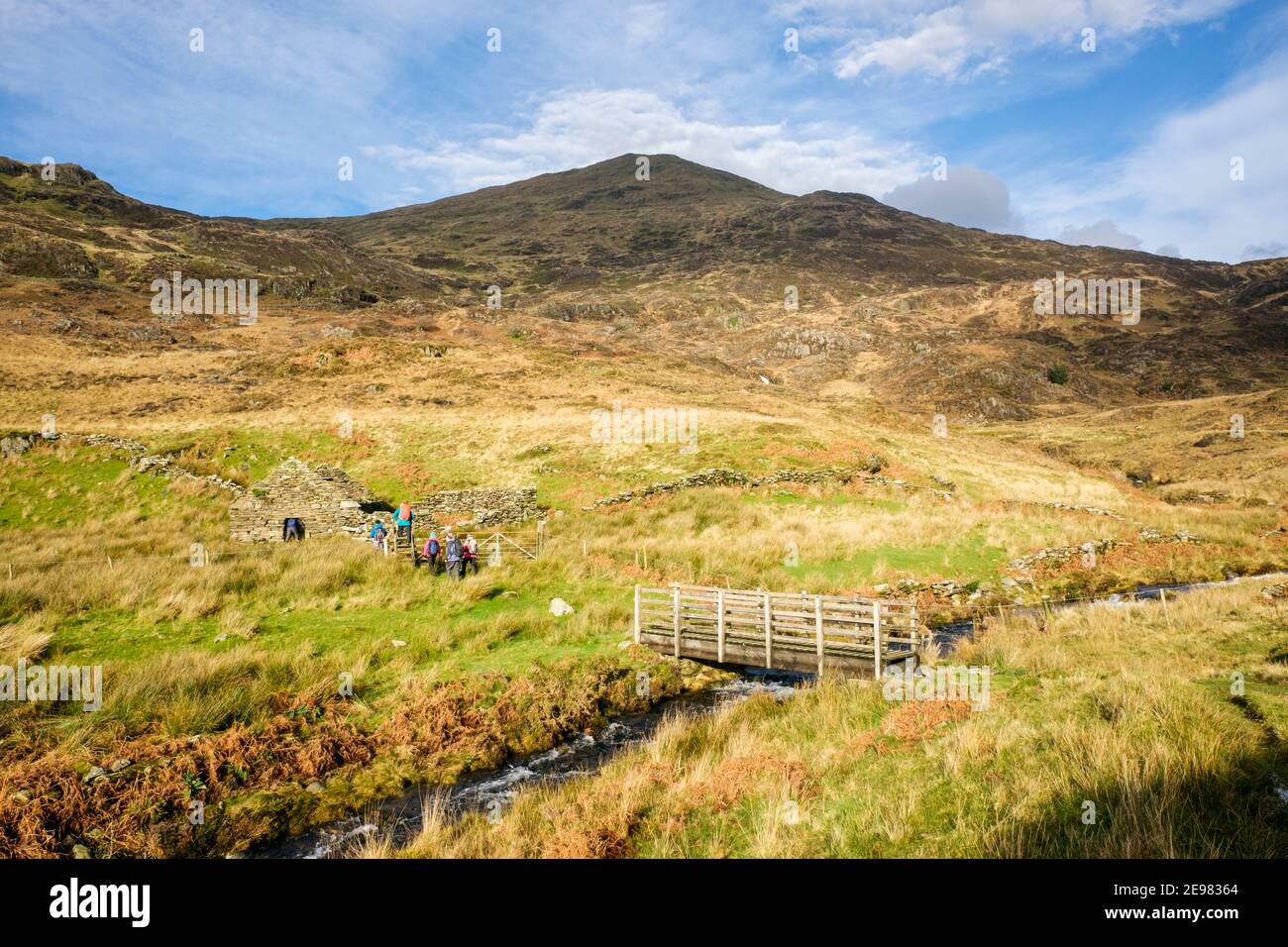 YR Aran montagne et une passerelle au-dessus d'un ruisseau avec des randonneurs sur le sentier dans le parc national de Snowdonia. Bethania, Beddgelert, Gwynedd, pays de Galles, Royaume-Uni, Grande-Bretagne Banque D'Images