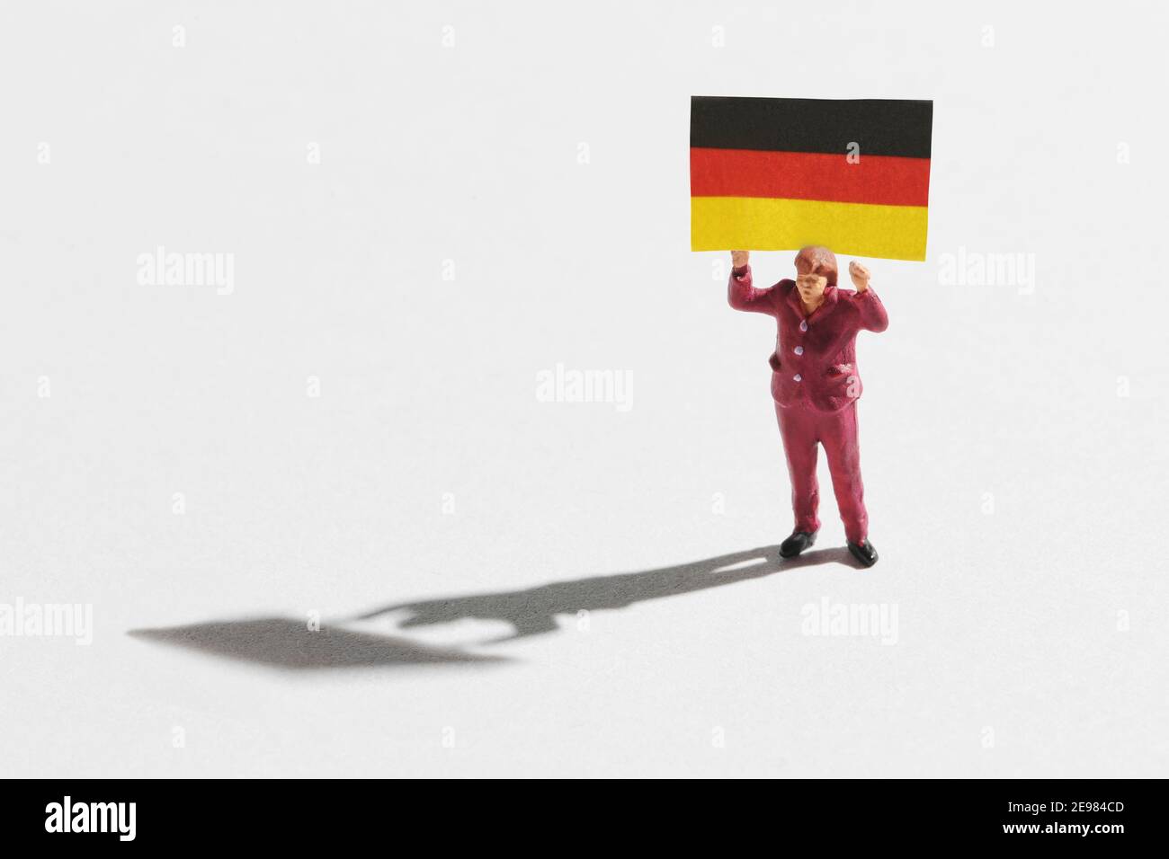 Figurine miniature de personnage féminin portant le drapeau allemand arrière-plan blanc avec ombre Banque D'Images