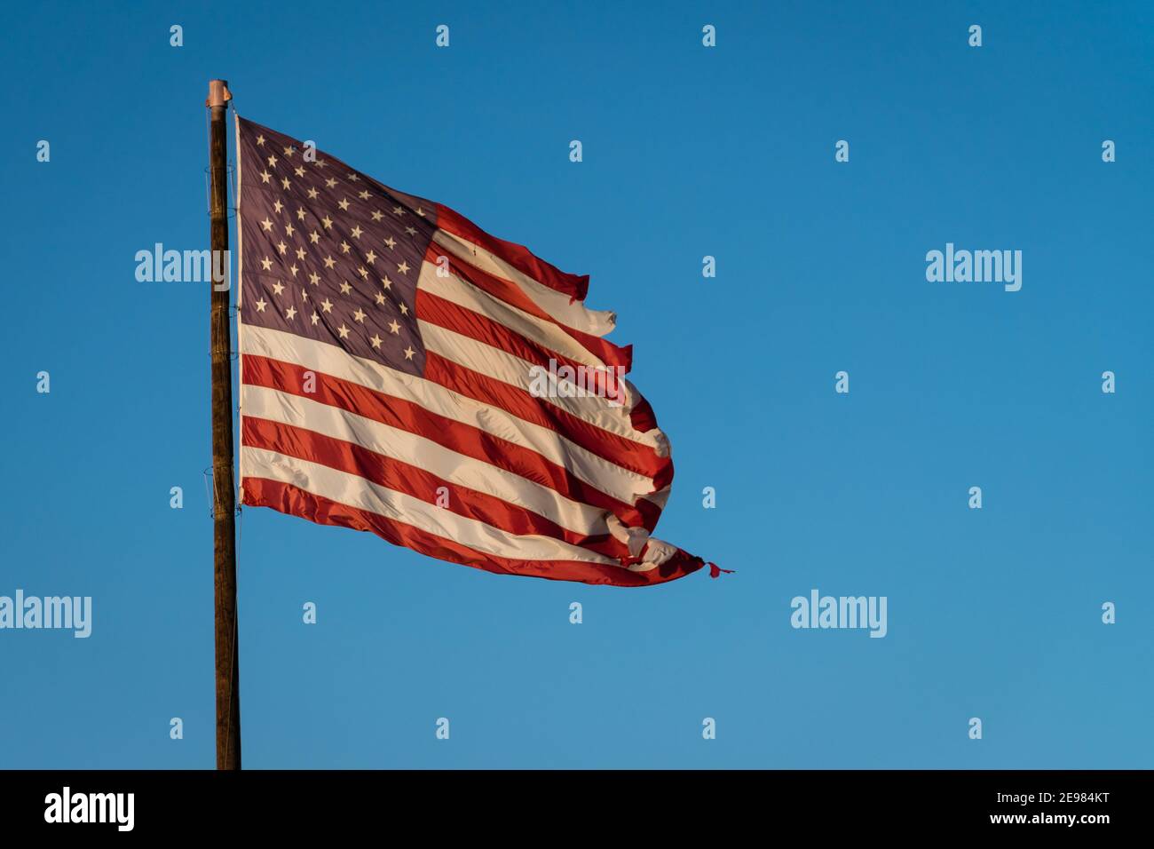 Drapeau américain flatté contre un ciel bleu brillant Banque D'Images