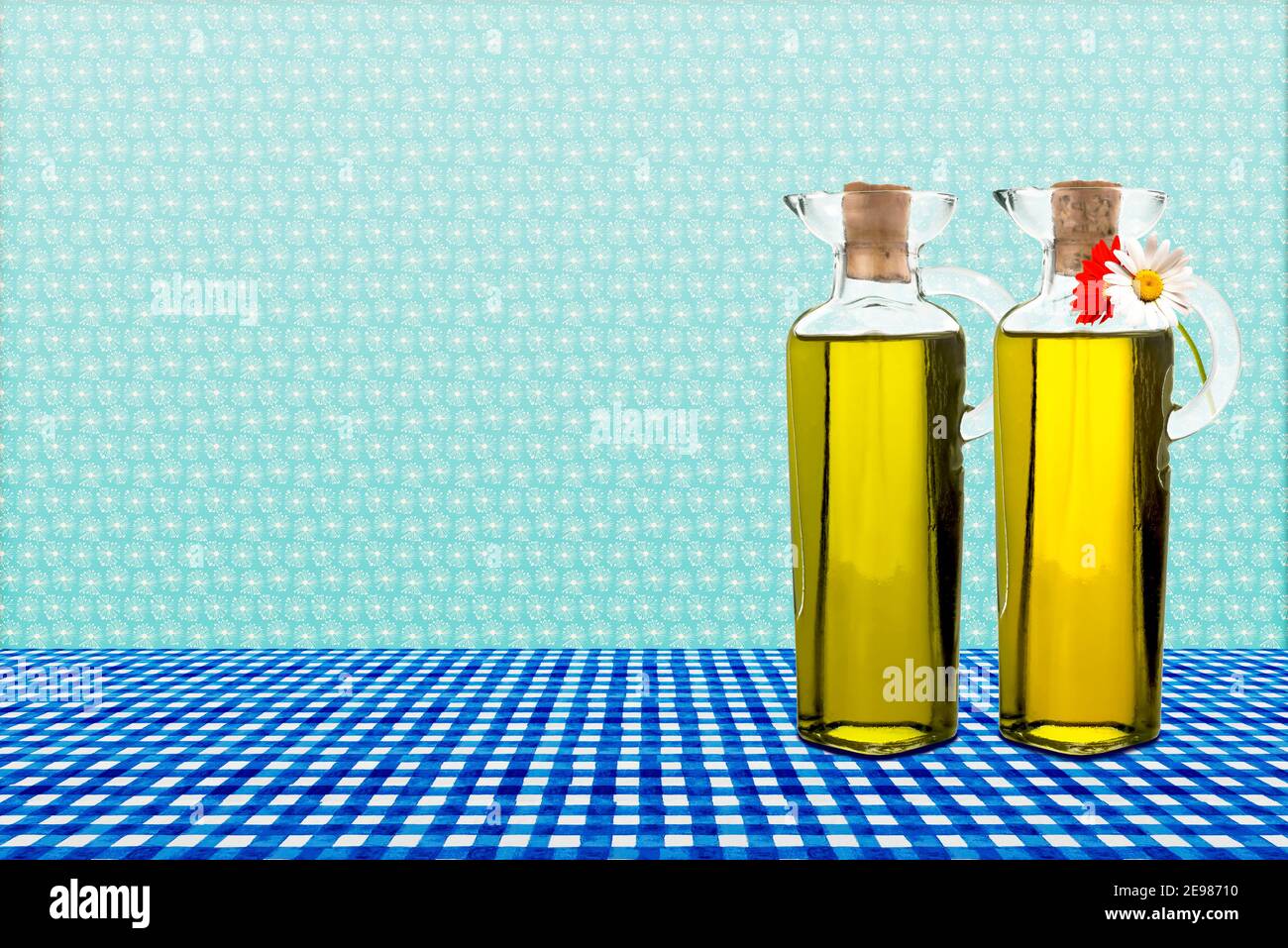 Huile d'olive extra vierge pressée à froid dans deux bouteilles de verre avec deux pâquerettes sur un fond de cuisine rétro avec espace vide. Banque D'Images