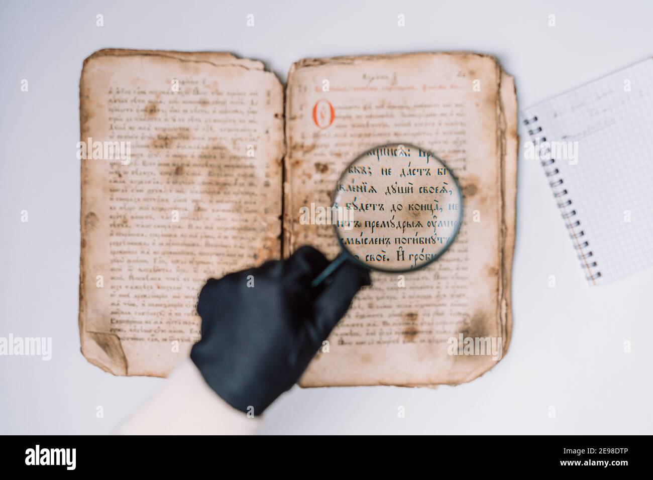 Historien scientifique en gants lisant livre antique avec loupe. Traduction  de la littérature religieuse. Manuscrit avec des écrits anciens Photo Stock  - Alamy
