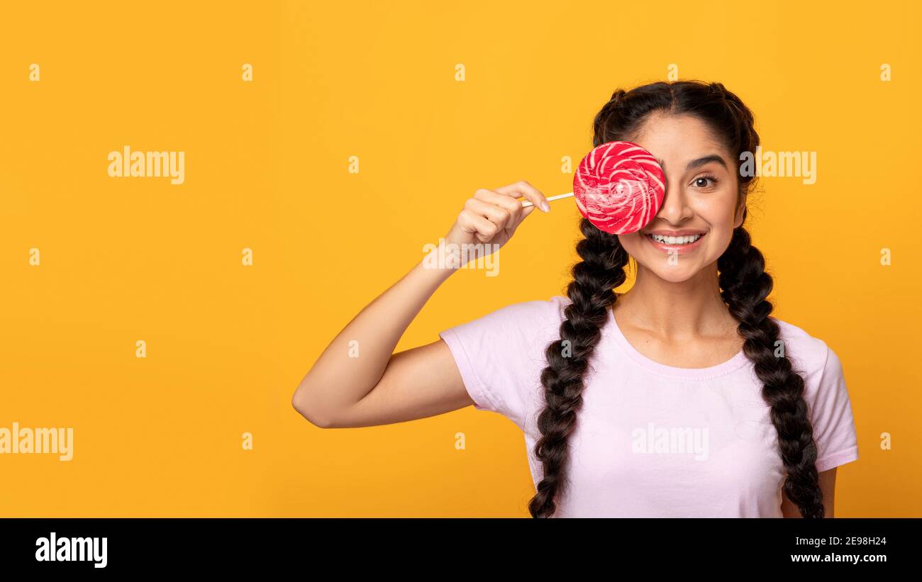 Femme indienne tenant une lollipop, couvrant l'œil avec des bonbons Banque D'Images