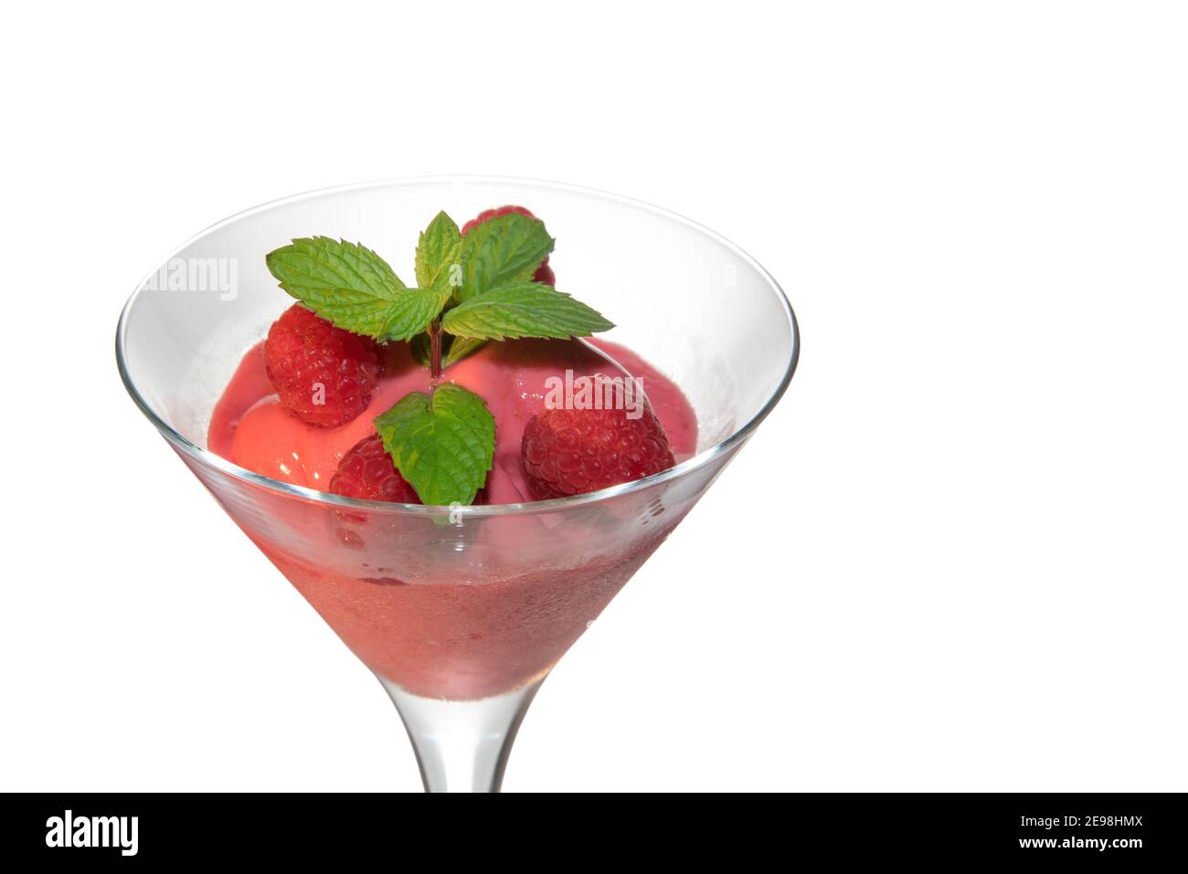 sorbet crème glacée framboises en verre martini avec feuilles de menthe verte isolées sur blanc, gros plan, espace de copie Banque D'Images