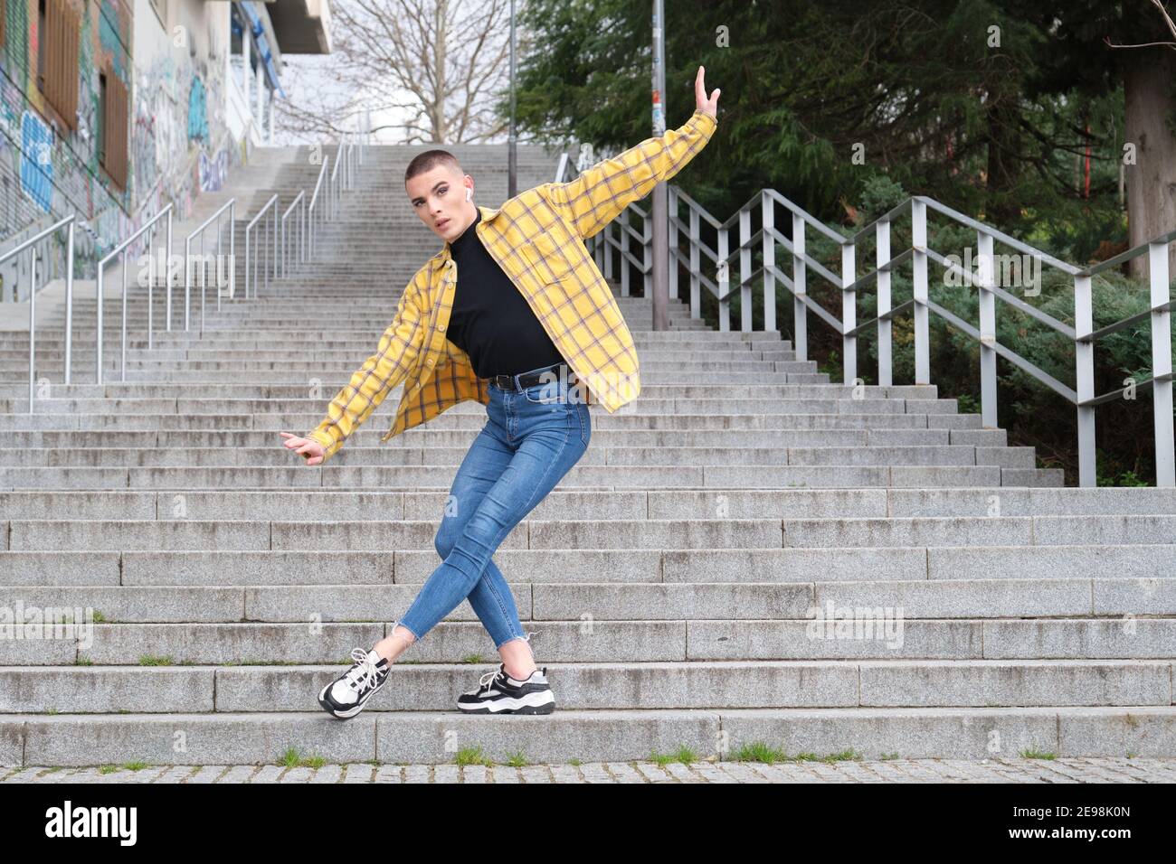 Beau jeune homme portant du maquillage, dansant le ballet dans les escaliers. Type androgyne non binaire. Banque D'Images