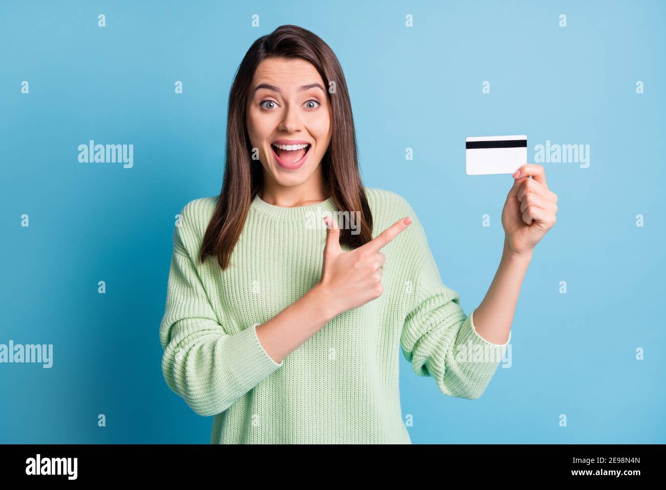 Photo portrait d'une femme excitée pointant le doigt sur le plastique carte isolée sur fond bleu pastel Banque D'Images