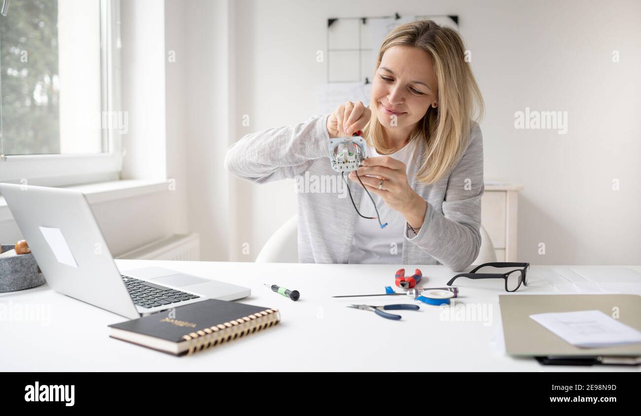 belle, blonde femme électricien assis à la table dans le bureau fixant une  prise Photo Stock - Alamy