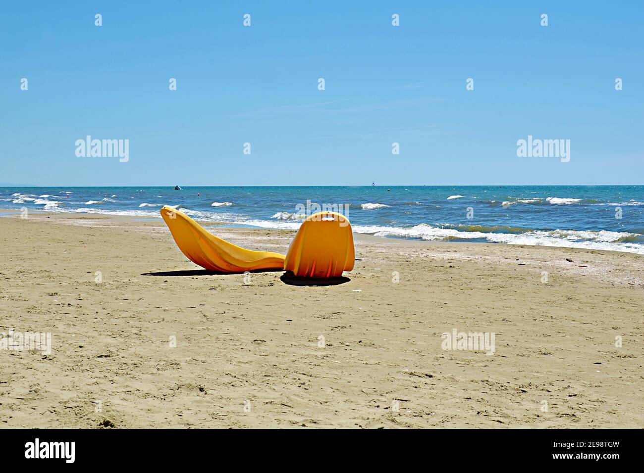 Deux chaises longues orange vides au bord de l'océan sur la Riviera italienne Pietrasanta, en attente au bord de la mer, sur laquelle les gens peuvent s'asseoir, sous la chaleur du soleil de printemps Banque D'Images