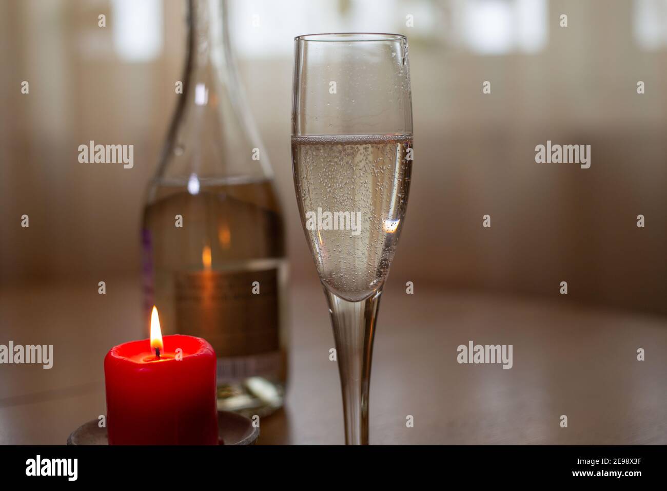 Vin blanc mousseux, verre et bougie sur la table 2021 Banque D'Images