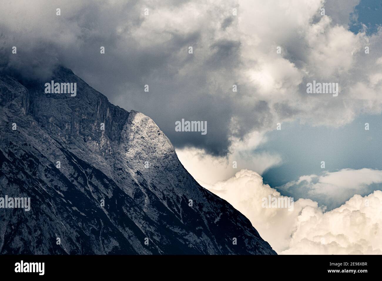 Nuage de tempête sur un flanc de montagne avec un point de lumière du soleil sur les rochers Banque D'Images