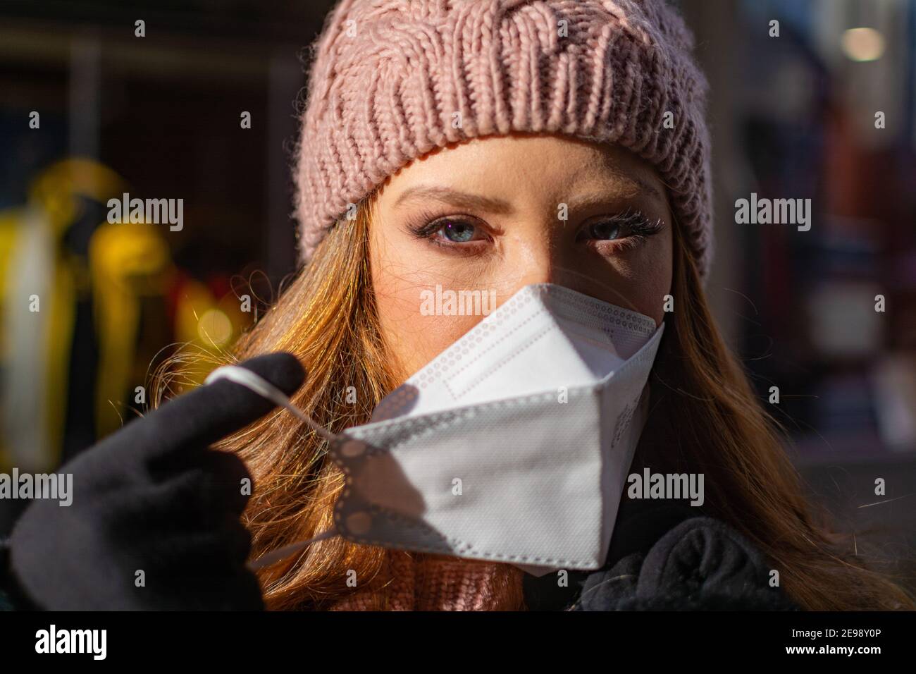 Bonne jeune femme avec les yeux bleus et les cheveux de gingembre en retrait Un masque protecteur pour le visage (FFP-2) pendant la pandémie de COVD-19 Banque D'Images